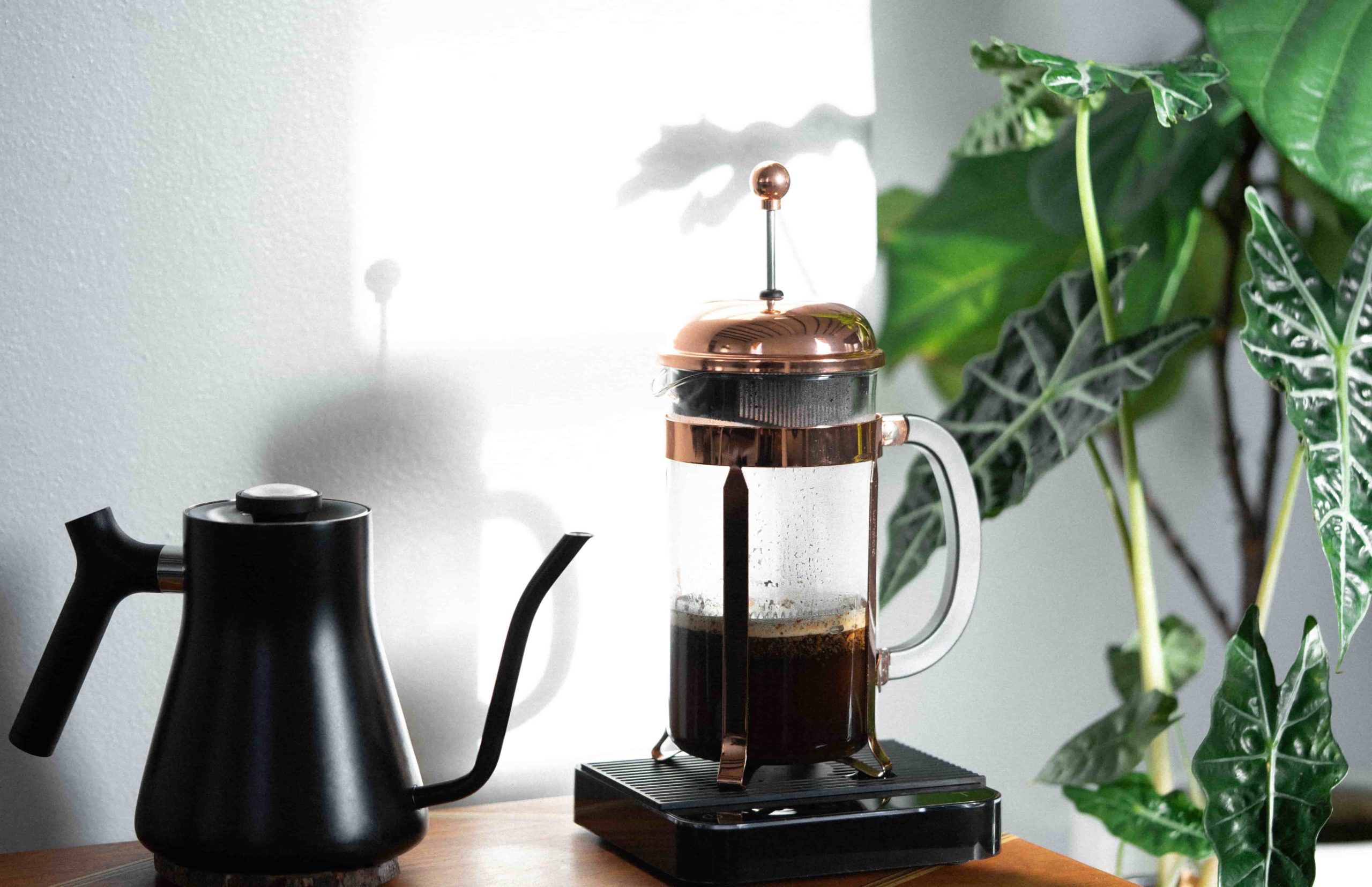 A matte black Fellow Kettle next to a freshly roasted brewed coffee from Puerto Rico in a Copper Bodum French Press on top of a Acaia Coffee Scale